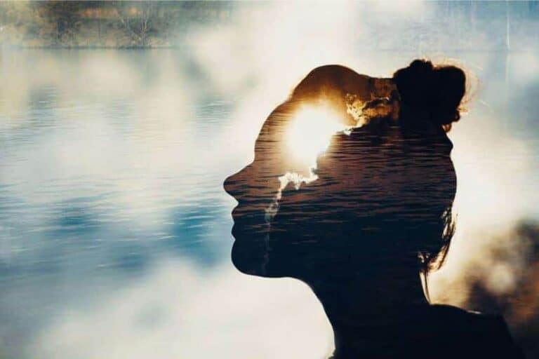 A woman with a silhouette with water against clouds and sunshine.