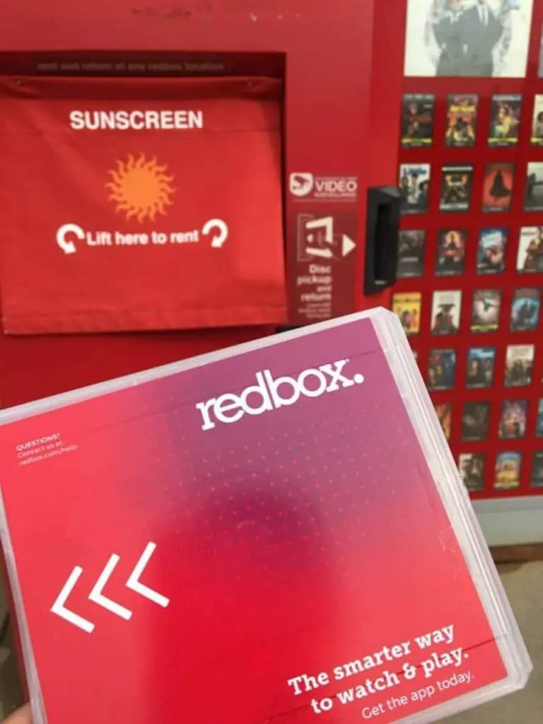 A person returning a Redbox DVD to the Redbox machine.