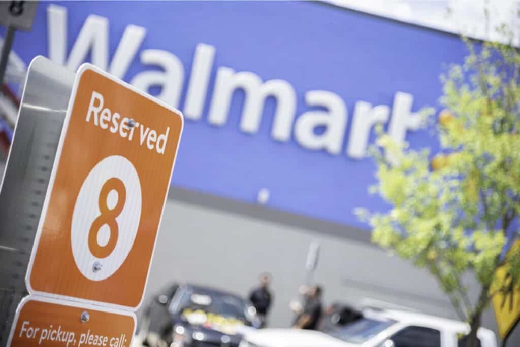 Close-up of a Reserved Pickup sign for number 8, set against the blurred backdrop of a Walmart building and parking lot, promising convenient access to your grocery needs, perhaps even with a handy coupon in hand.