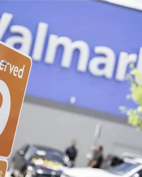 Close-up of a Reserved Pickup sign for number 8, set against the blurred backdrop of a Walmart building and parking lot, promising convenient access to your grocery needs, perhaps even with a handy coupon in hand.