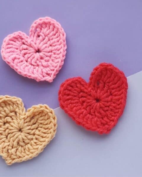 Pink, red, and tan crochet hearts.