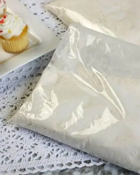 A bag of yellow cupcake mix with yellow cupcakes with white frosting.