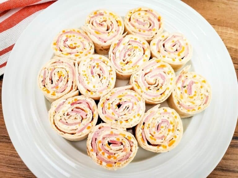 A white plate of pinwheel sandwiches.