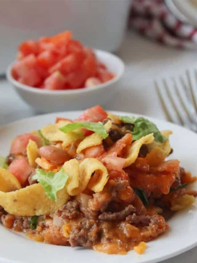 A plate full of walking tacos with Fritos and toppings.