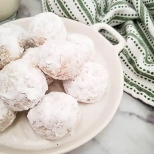 Finished snowball cookies on a white platter.