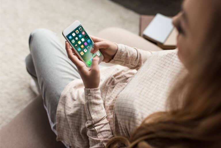 A woman on her smart phone while sitting on the floor.