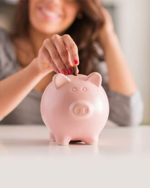 A woman putting money in a piggy bank.