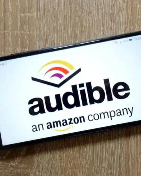 A smart phone with the Audible Amazon app open. The phone is laying faceup on the table.