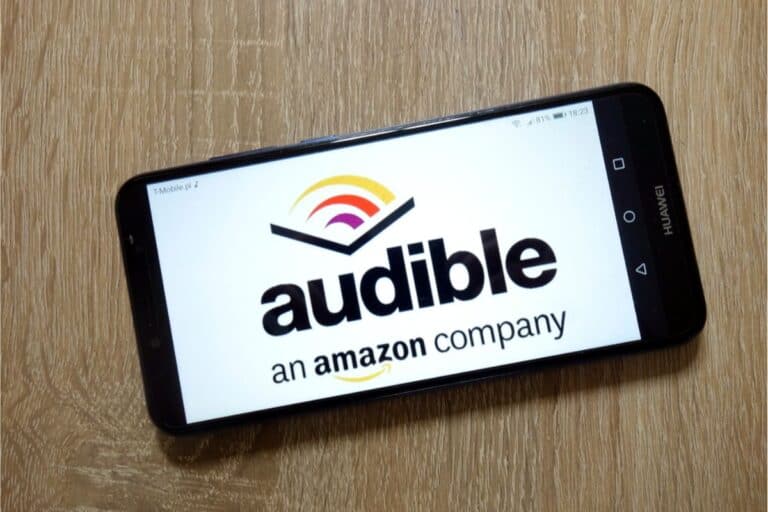 A smart phone with the Audible Amazon app open. The phone is laying faceup on the table.