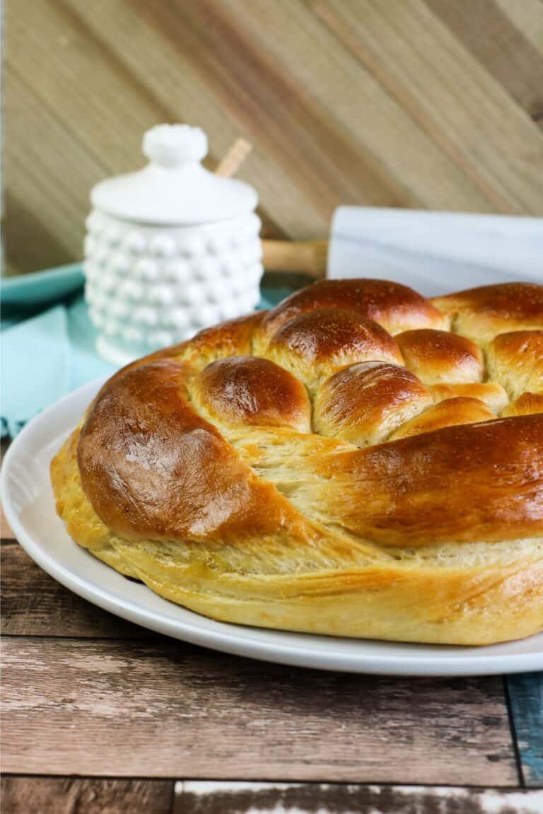 A plate of cooked challah bread that has been braided.