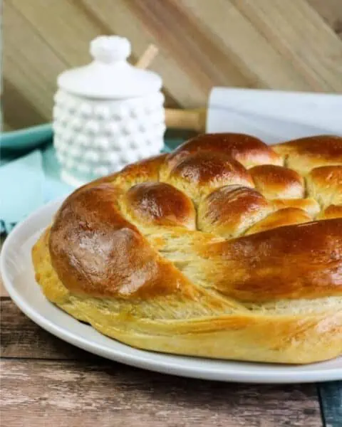 A plate of cooked challah bread that has been braided.