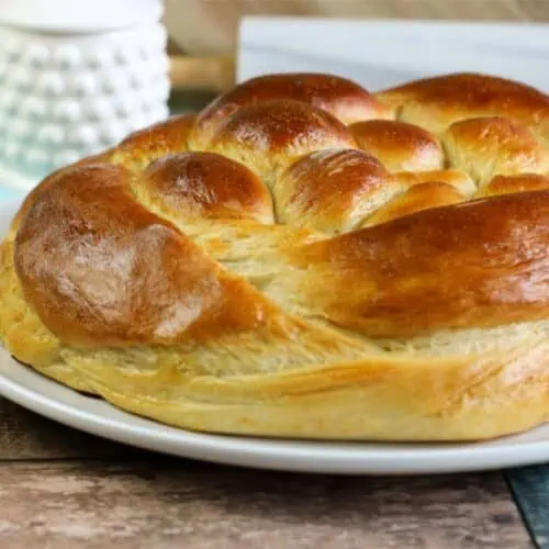 Golden and cooked challah bread on a white plate ready to be served.