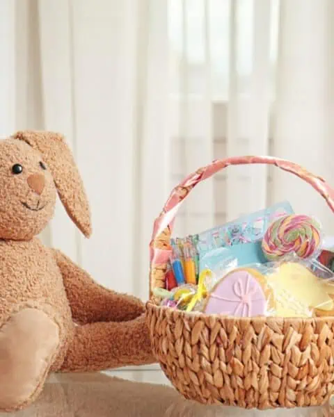 An adorable teddy bear surrounded by Easter basket stuffers.