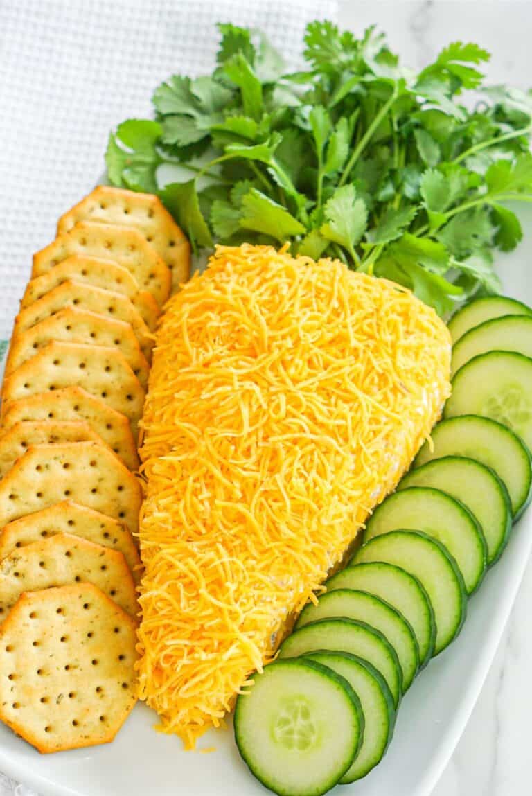 Easy carrot cheese dip served with crackers and cucumbers on a white plate.