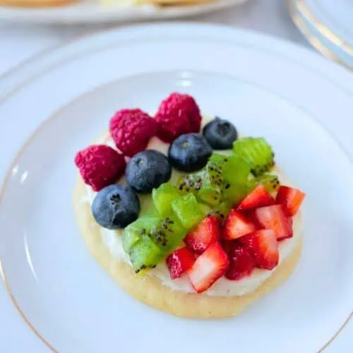 A plate with mini fruit pizzas decorated with berries.