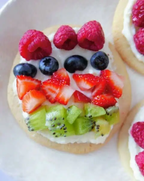 A plate of mini fruit pizzas topped with whipped cream.