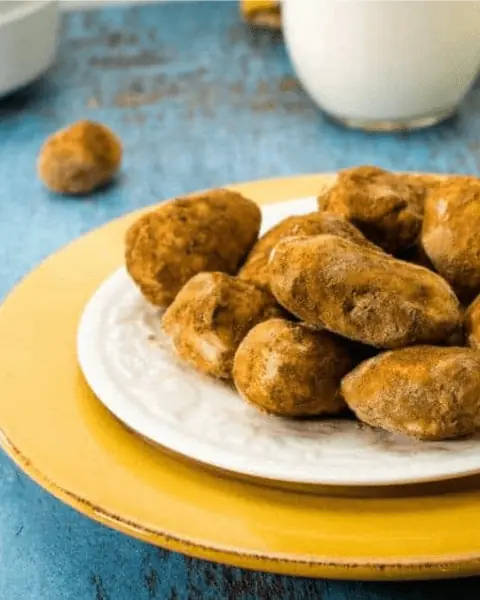 A plate of Irish Potato Candy truffles on a blue table.