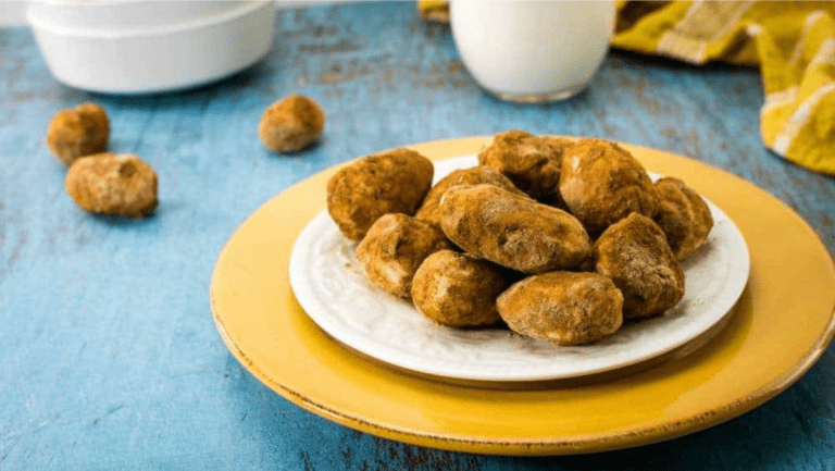 A plate of Irish Potato Candy truffles on a blue table.