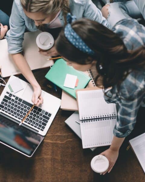 A group of students sitting around a table with laptops, utilizing useful gifts.