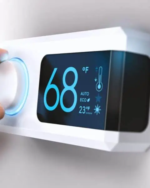 A person is saving money on power by adjusting the temperature on a smart thermostat.