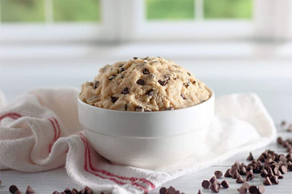 A bowl of edible chocolate chip cookie dough ice cream garnished with chocolate chips.