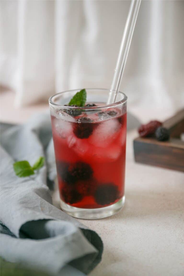 A refreshing Very Berry Hibiscus iced tea with a blackberry twist, garnished with a straw.