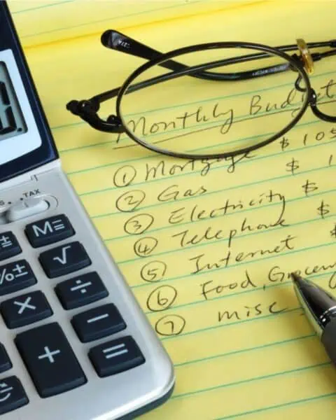 A cost-cutting calculator equipped with glasses and a pen on a piece of paper.