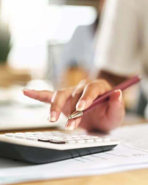 A woman avoids household budgeting mistakes by using a calculator on her desk.