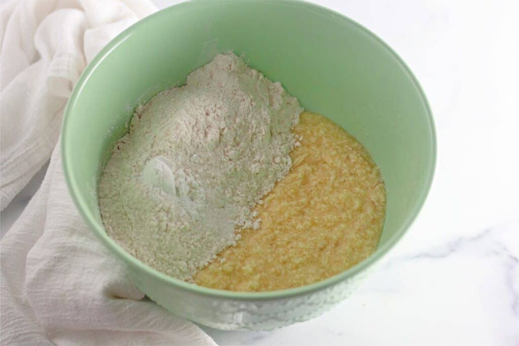 A green bowl with flour and eggs in it, preparing the Banana Chocolate Chip Muffins Recipe.