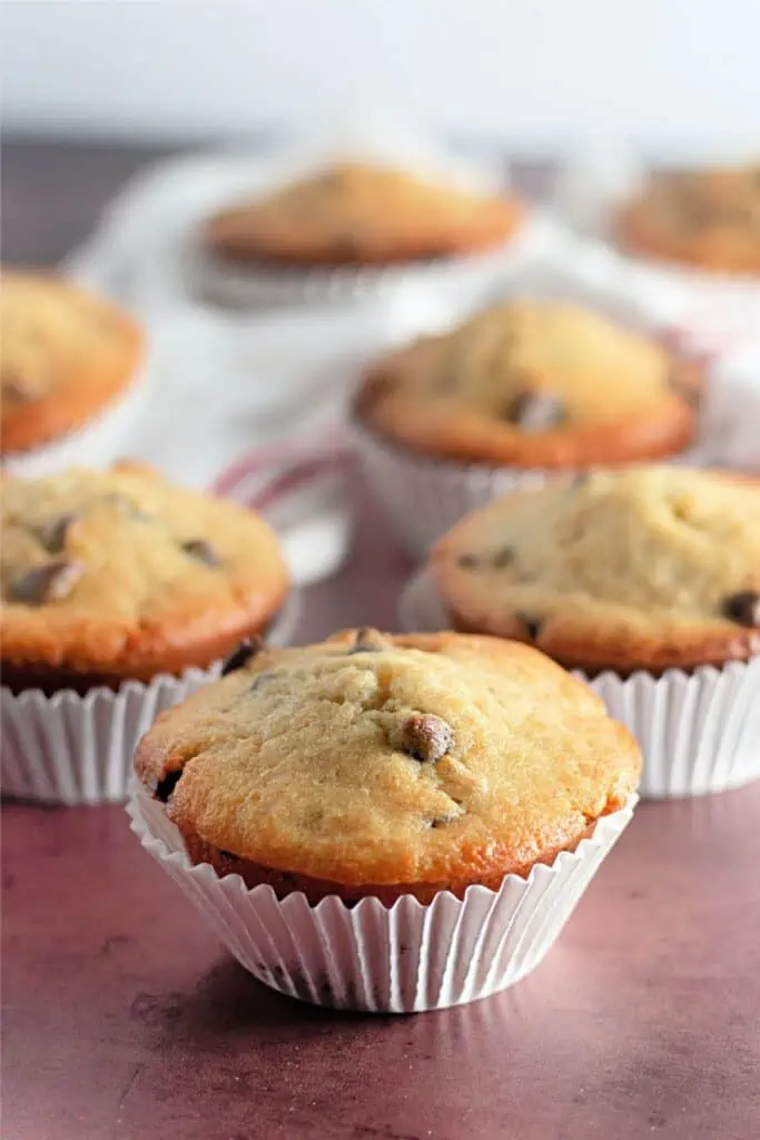 Banana chocolate chip muffins in paper cups on a table.