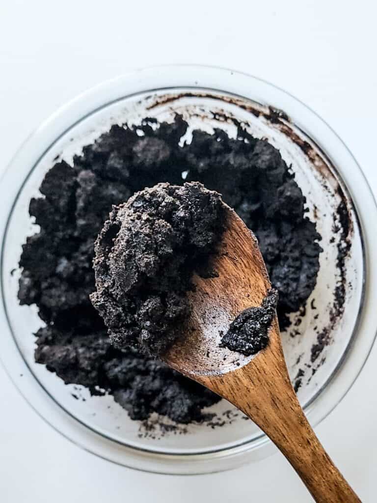 A wooden spoon is placed in a bowl of mint chocolate chip ice cream.