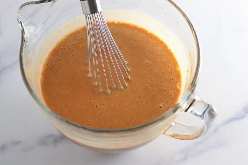 A whisk in a bowl of sauce, like Pumpkin Cobbler.