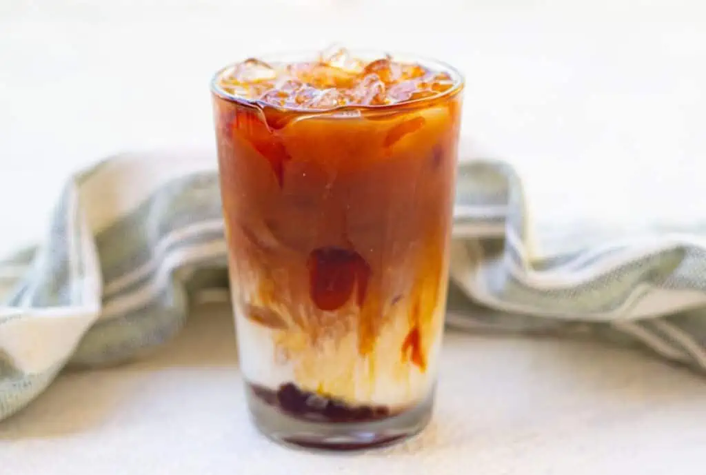 A Starbucks Iced Caramel Macchiato is sitting on a table next to a napkin.