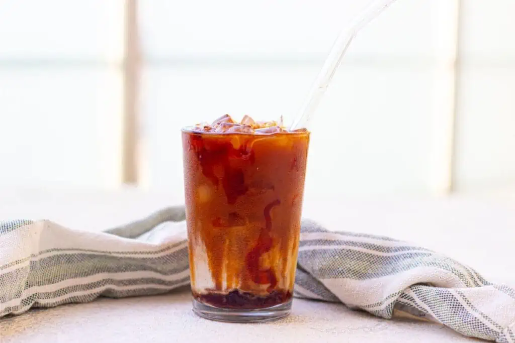 A Starbucks Iced Caramel Macchiato with a straw sitting on a table.