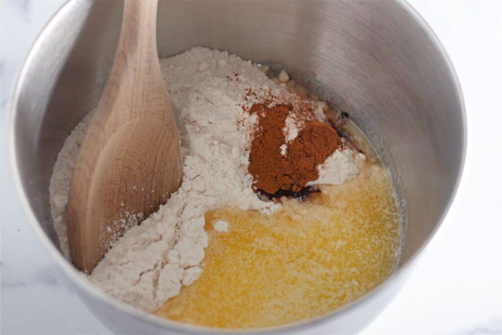 A pumpkin cobbler served in a metal bowl with a wooden spoon.