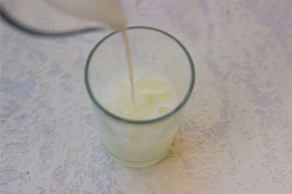 A glass of milk being poured into a glass, reminiscent of a Starbucks Iced Caramel Macchiato.