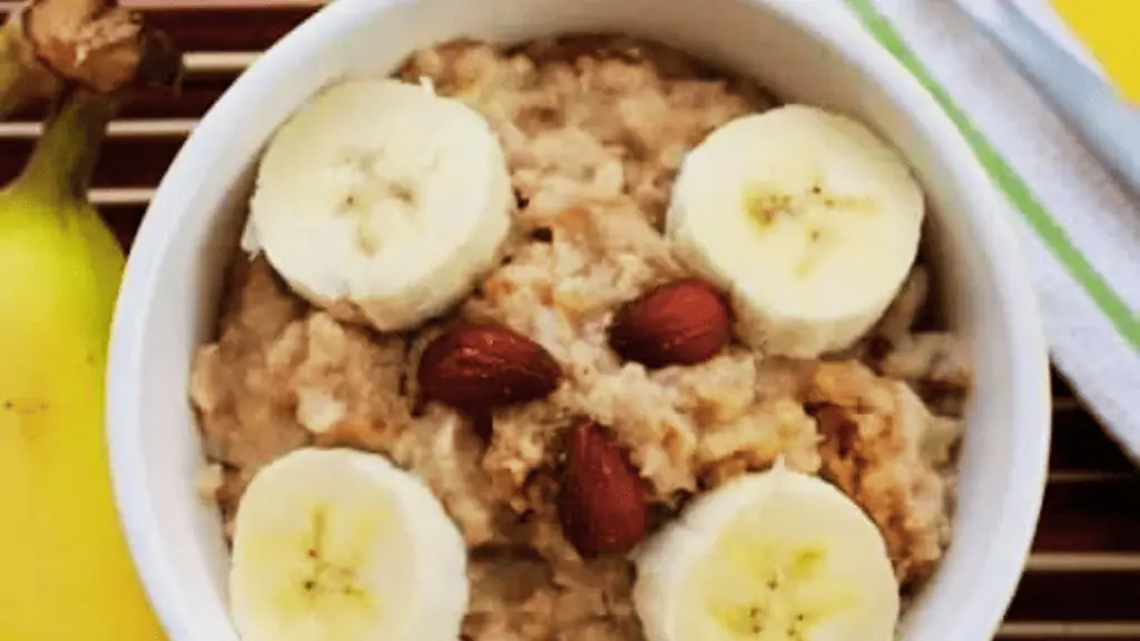A bowl of oatmeal topped with almonds and banana slices.