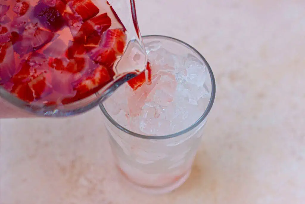 A glass of Strawberry Acai Refresher being poured into a glass.