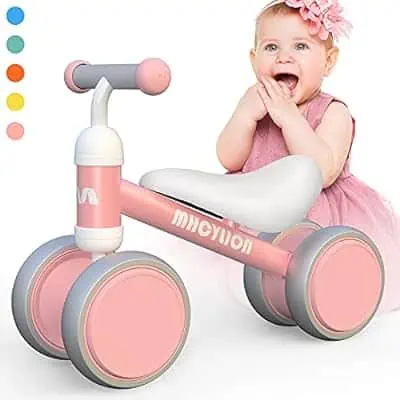 A baby is sitting on a pink balance bike, taking advantage of the October 31st Deals.