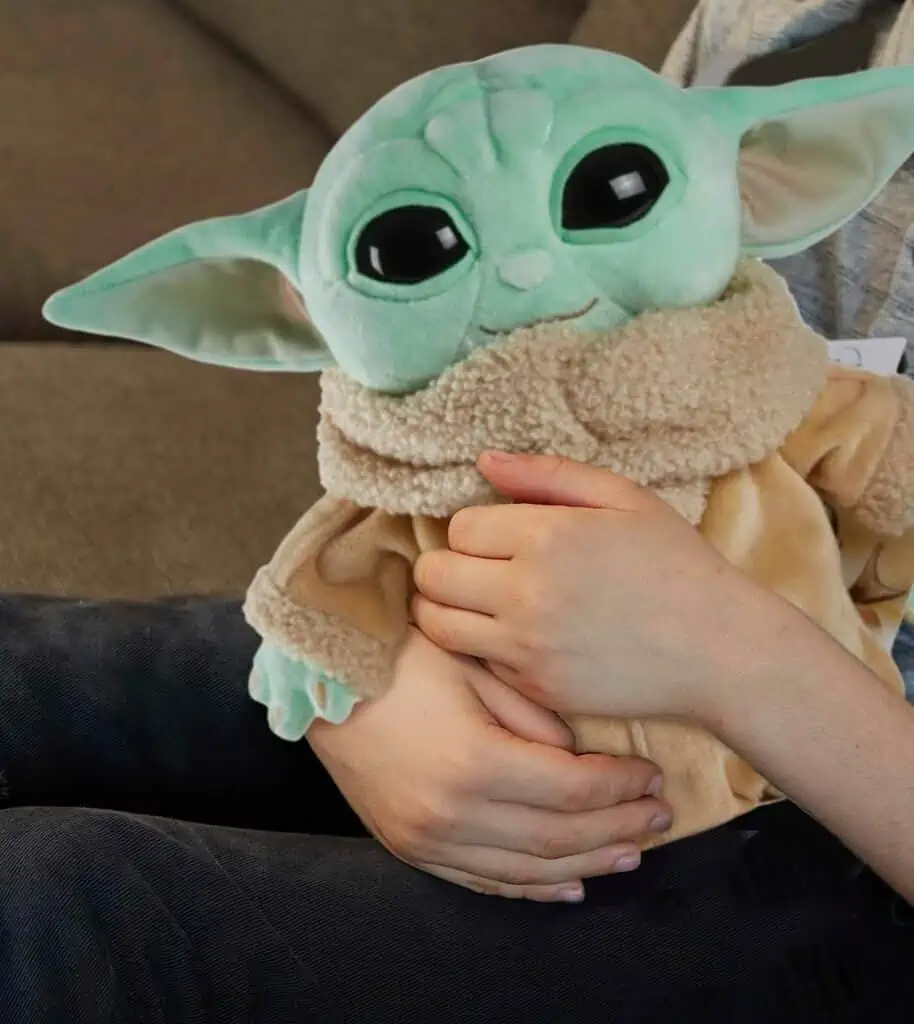 October 31st Deals: A child is holding a baby yoda plush toy available at discounted prices.