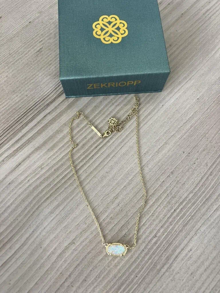 A gold necklace with an opalite stone in the box, perfect for deals on November 24th.