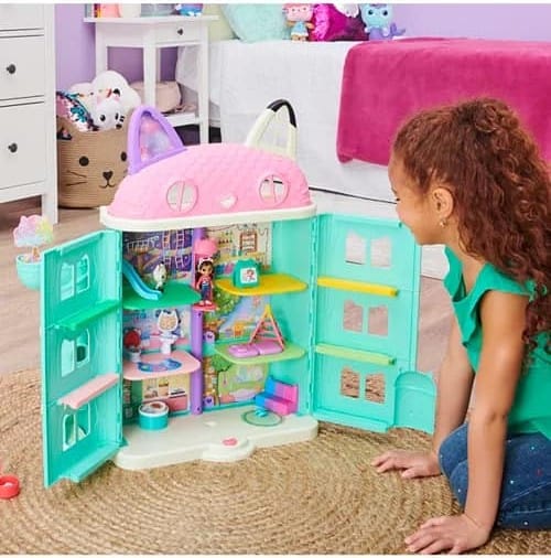 A little girl is happily playing with a toy house.
