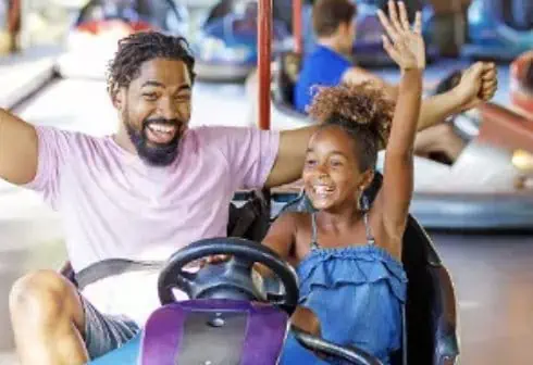 On November 25th, a man and a girl enjoy riding a bumper car at an amusement park, taking advantage of exciting Deals.