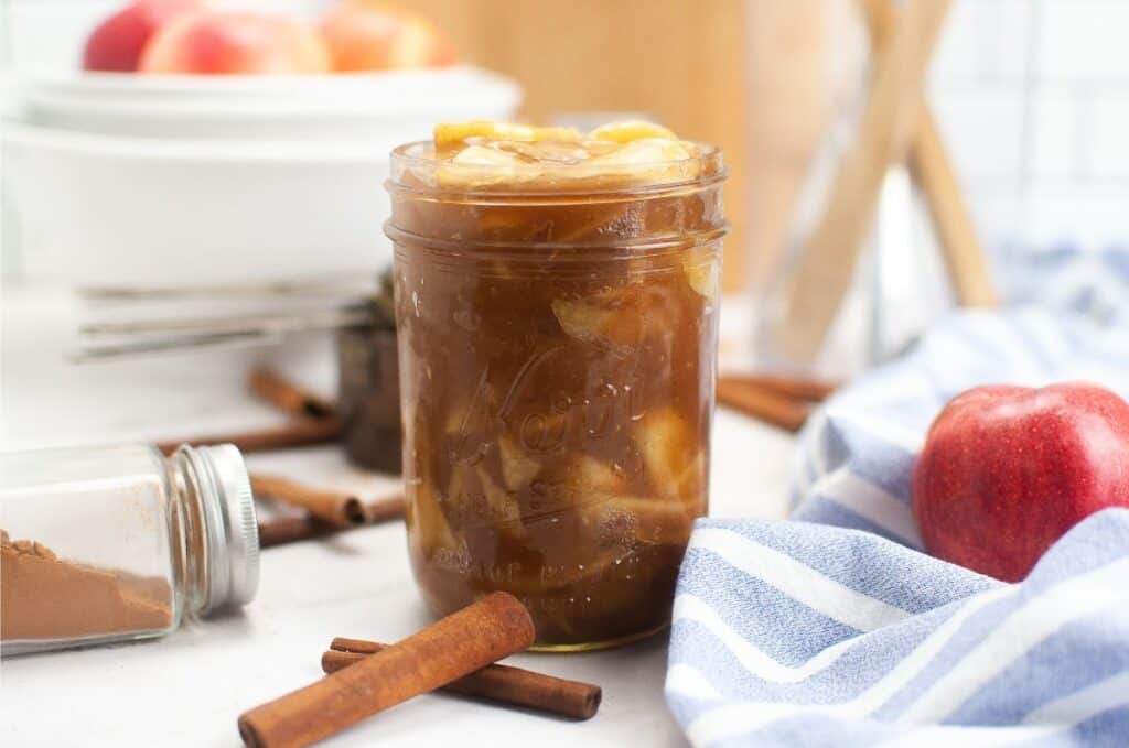 A mason jar filled with homemade apple pie filling, made with fresh apples and a sprinkle of cinnamon.