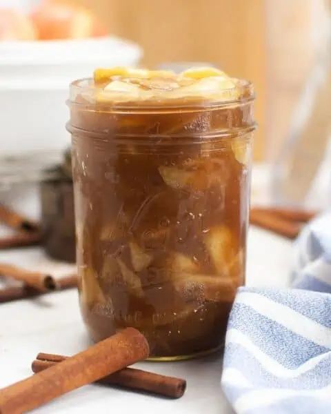 A mason jar filled with homemade apple pie filling, made with fresh apples and a sprinkle of cinnamon.