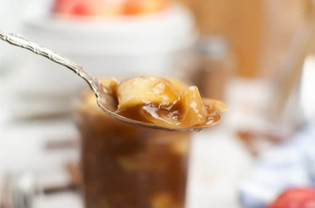 A spoon full of apple pie filling on a table.