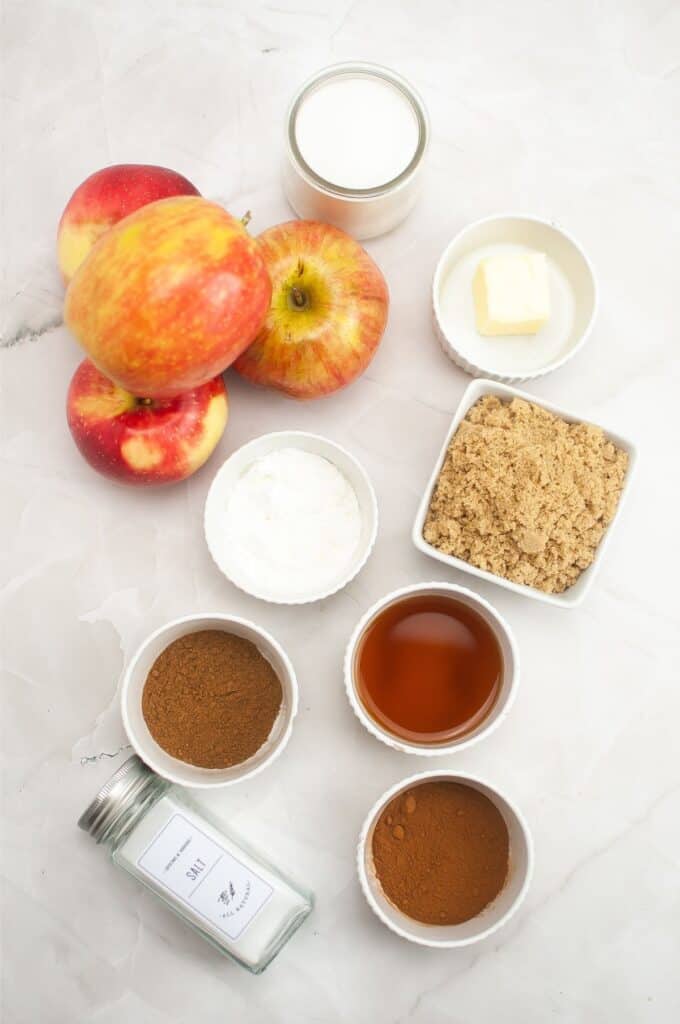 Apple pie filling ingredients on a marble table.
