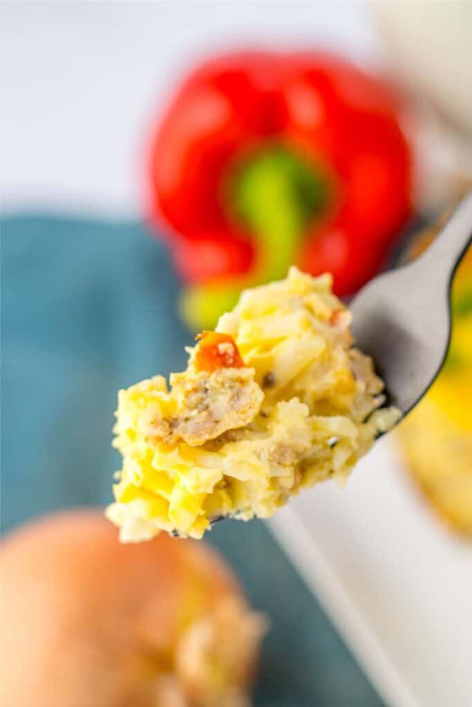 A slowcooker casserole is being held by a fork for breakfast.