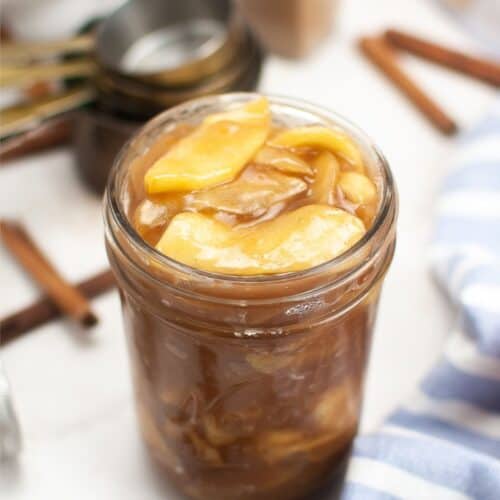 Apple pie filling in a jar with cinnamon sticks.