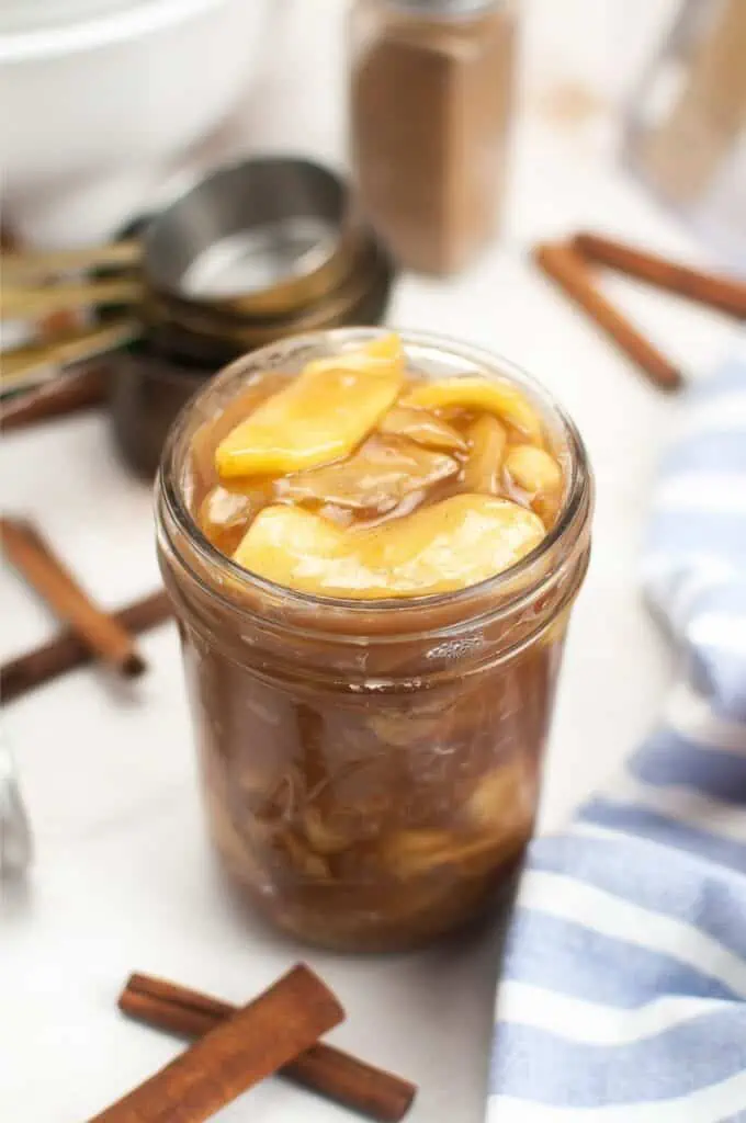 Apple pie filling in a jar with cinnamon sticks.